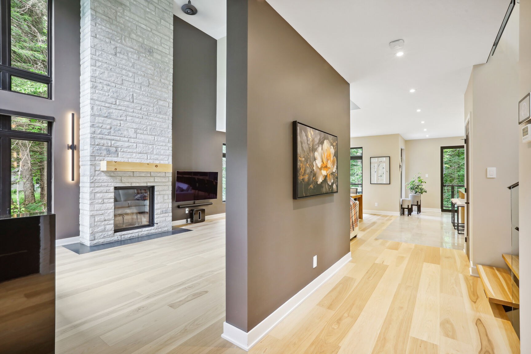 Salon cathédrale, grande fenestration et foyer au bois habillé de pierre.