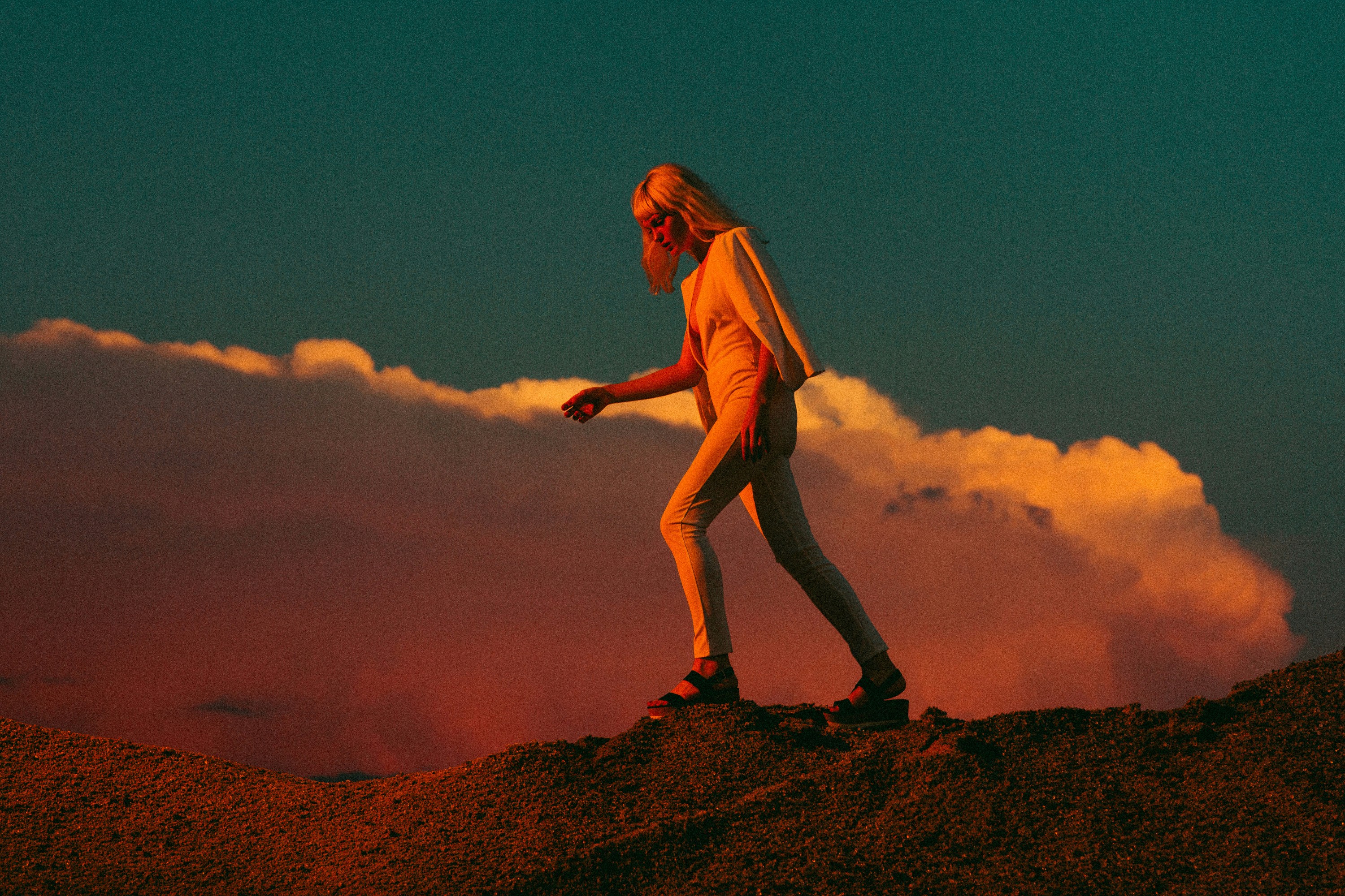 Person geht bedacht über eine erhöhte Landschaft vor weitem Himmel – visuelle Metapher für Orientierung, Klarheit und schrittweises Vorankommen.