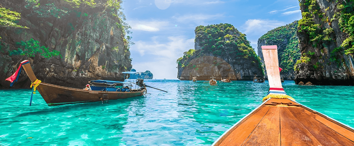 This image shows a traditional long-tail boat anchored in the turquoise waters of the Phi Phi Islands in Thailand