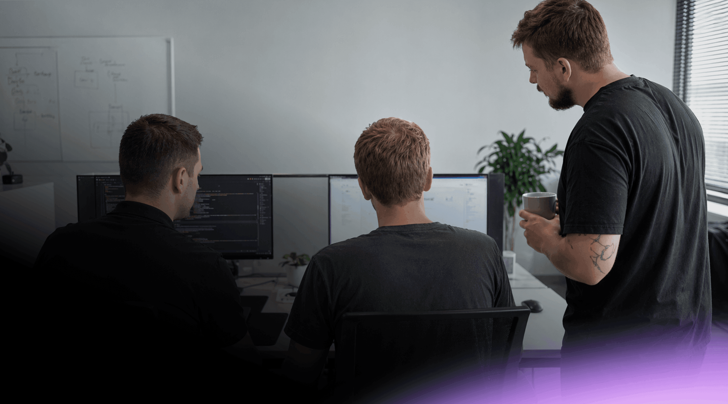 Nextio developers collaborating on custom software development and coding a web application on dual monitors.