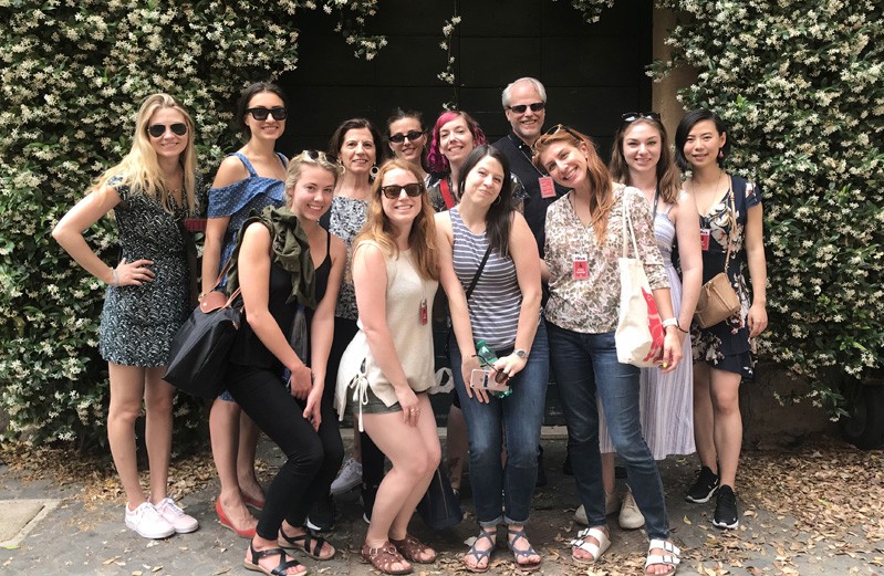 A photo of a group of people standing near a hedge.