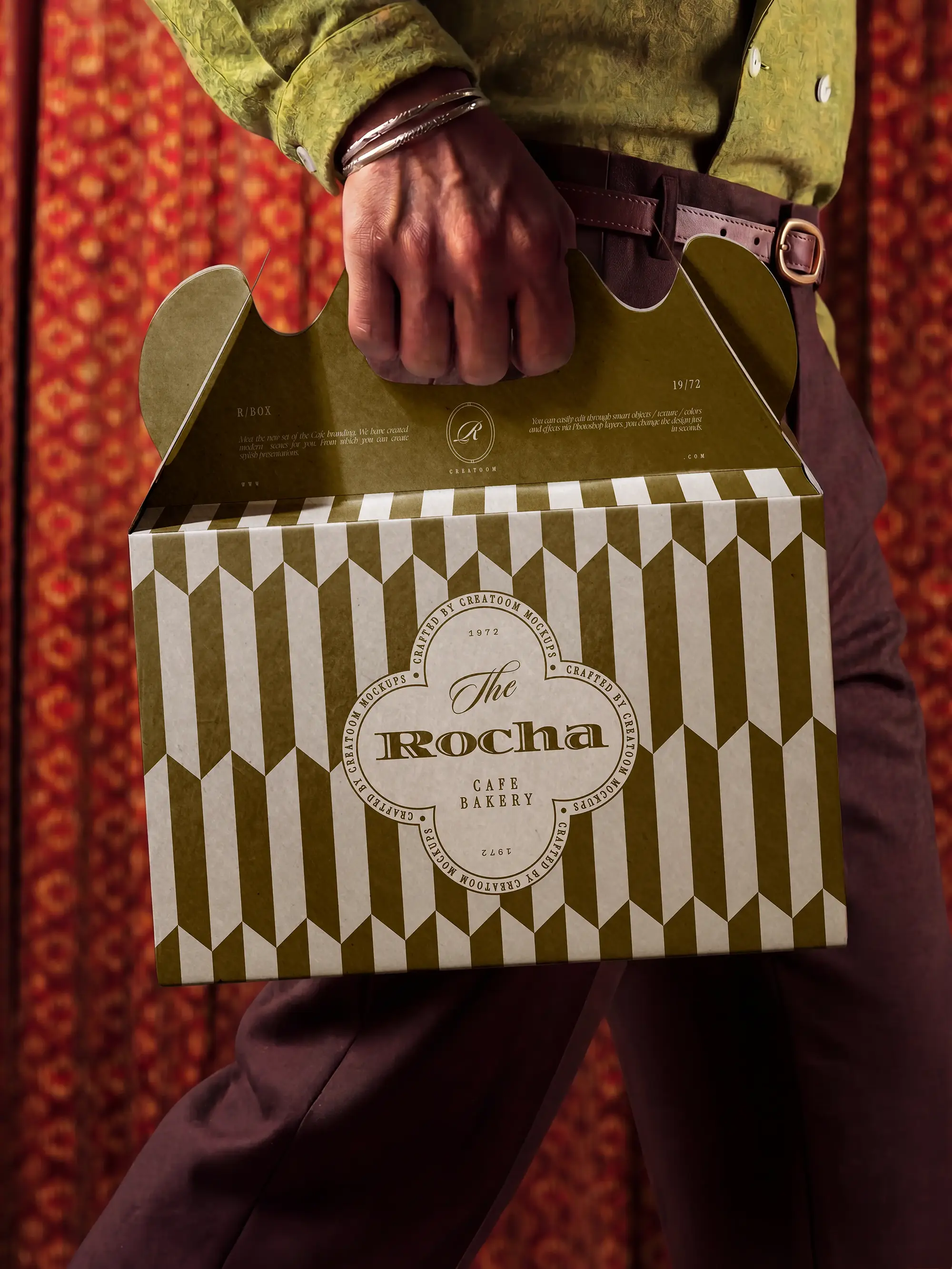 Person carrying an olive patterned cake box by its handle