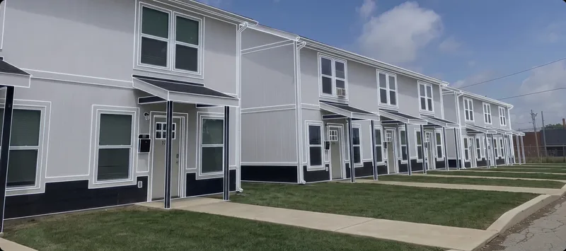 Suburban Triplex Builds: a row of white two-story townhome units with dark skirting and covered entries along a sidewalk