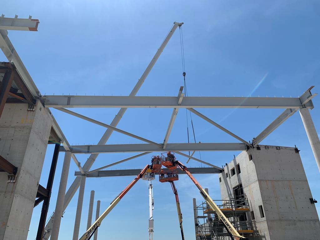 Construction workers on lift platforms installing steel beams.
