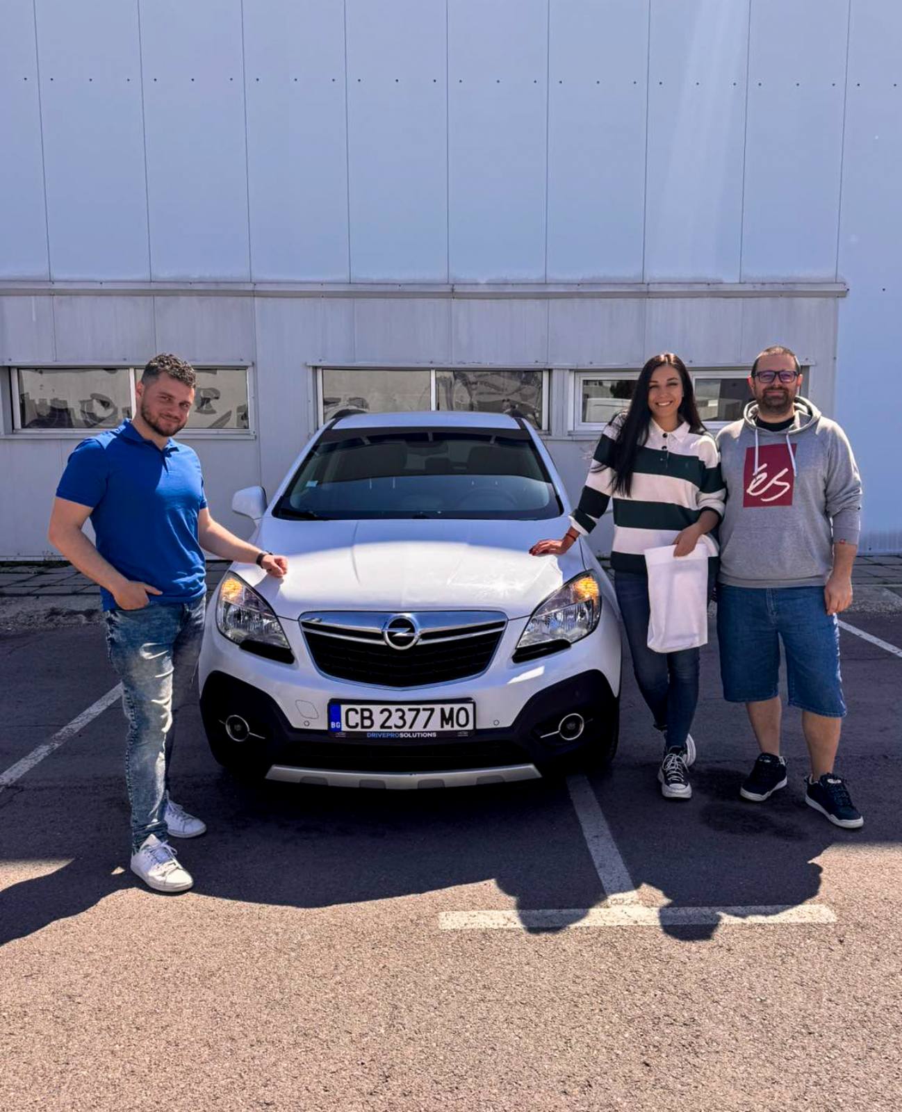 A car salesman and two happy customers nex to their new car