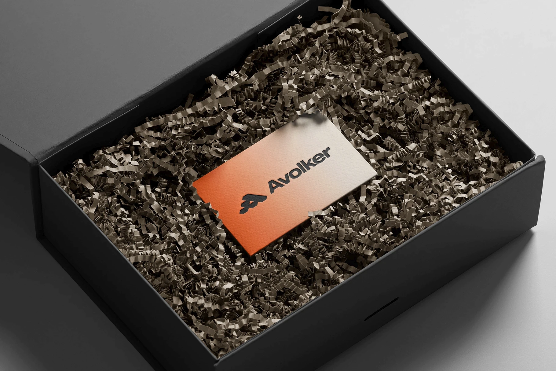 Logo mockup card inside a luxury black gift box with shredded paper filler.