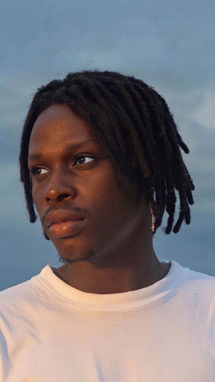 Asake in white T-shirt facing right in portrait view
