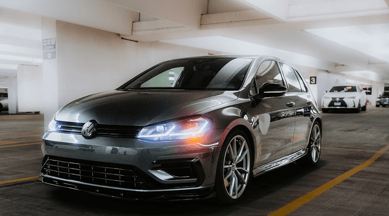 orange coupe parked near white and gray building