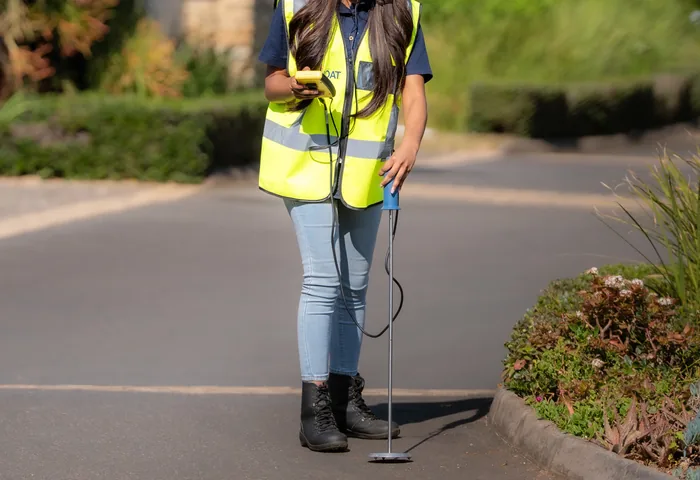 JOAT technician listening for a leak with a ground microphone on a residential street
