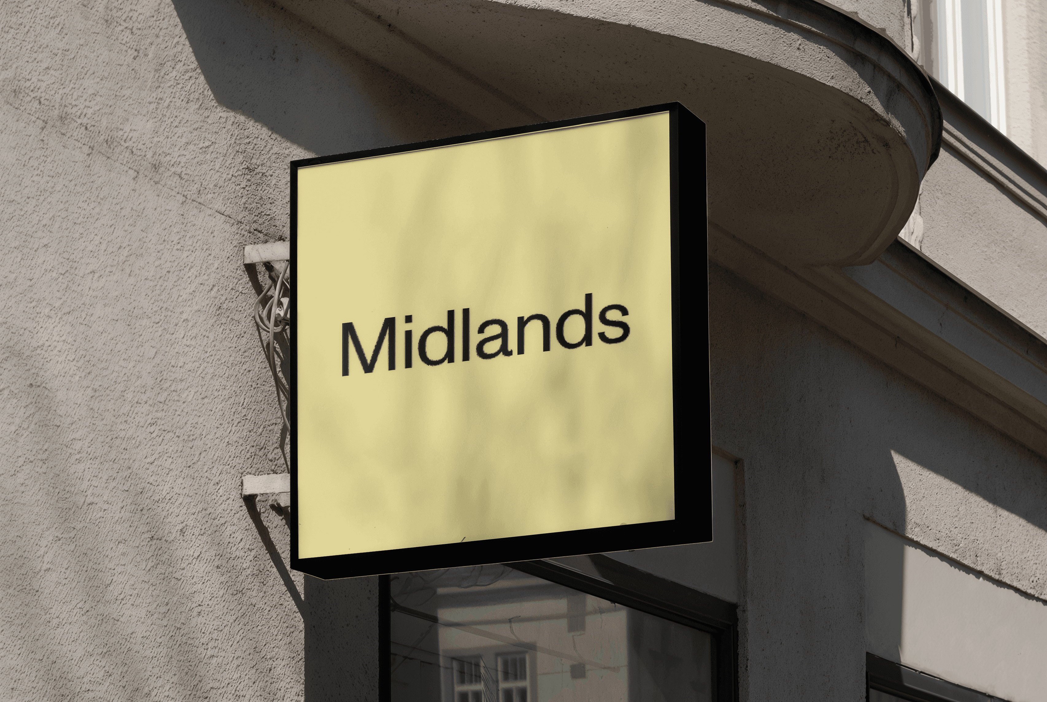 Exterior photo of a beige building with a yellow sign displaying the word “Midlands.”
