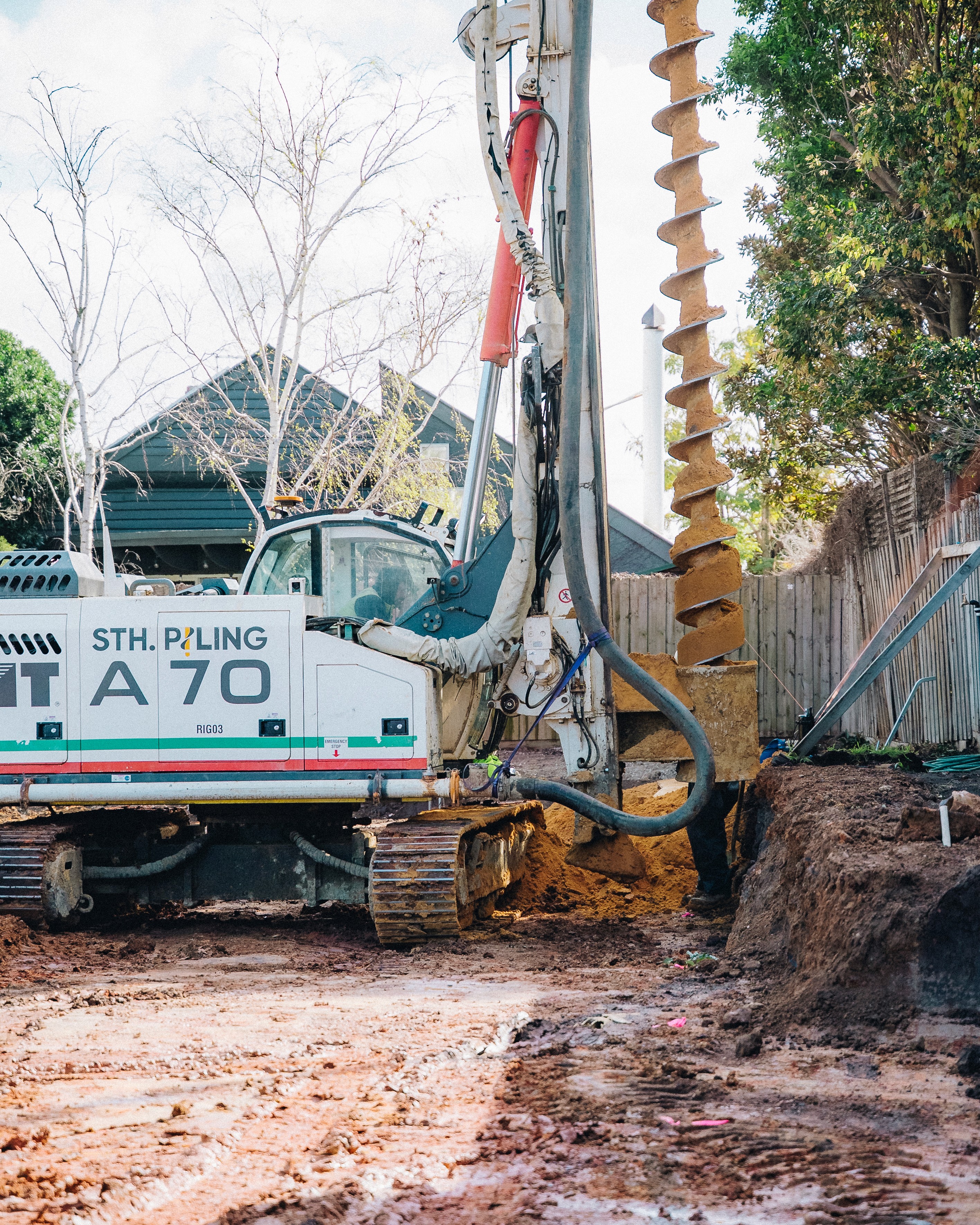 Construction site with heavy drilling machinery, soil excavation in progress.