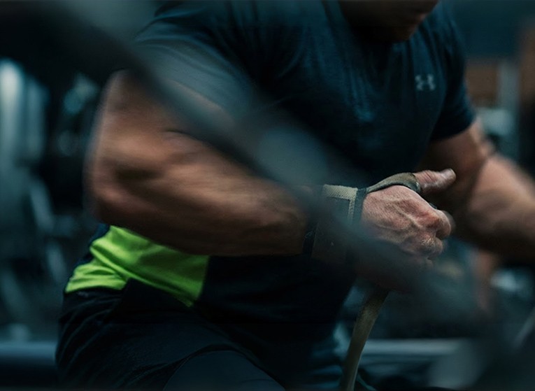 Close-up of a person's arm in a black shirt, adjusting a smartwatch in a gym setting.