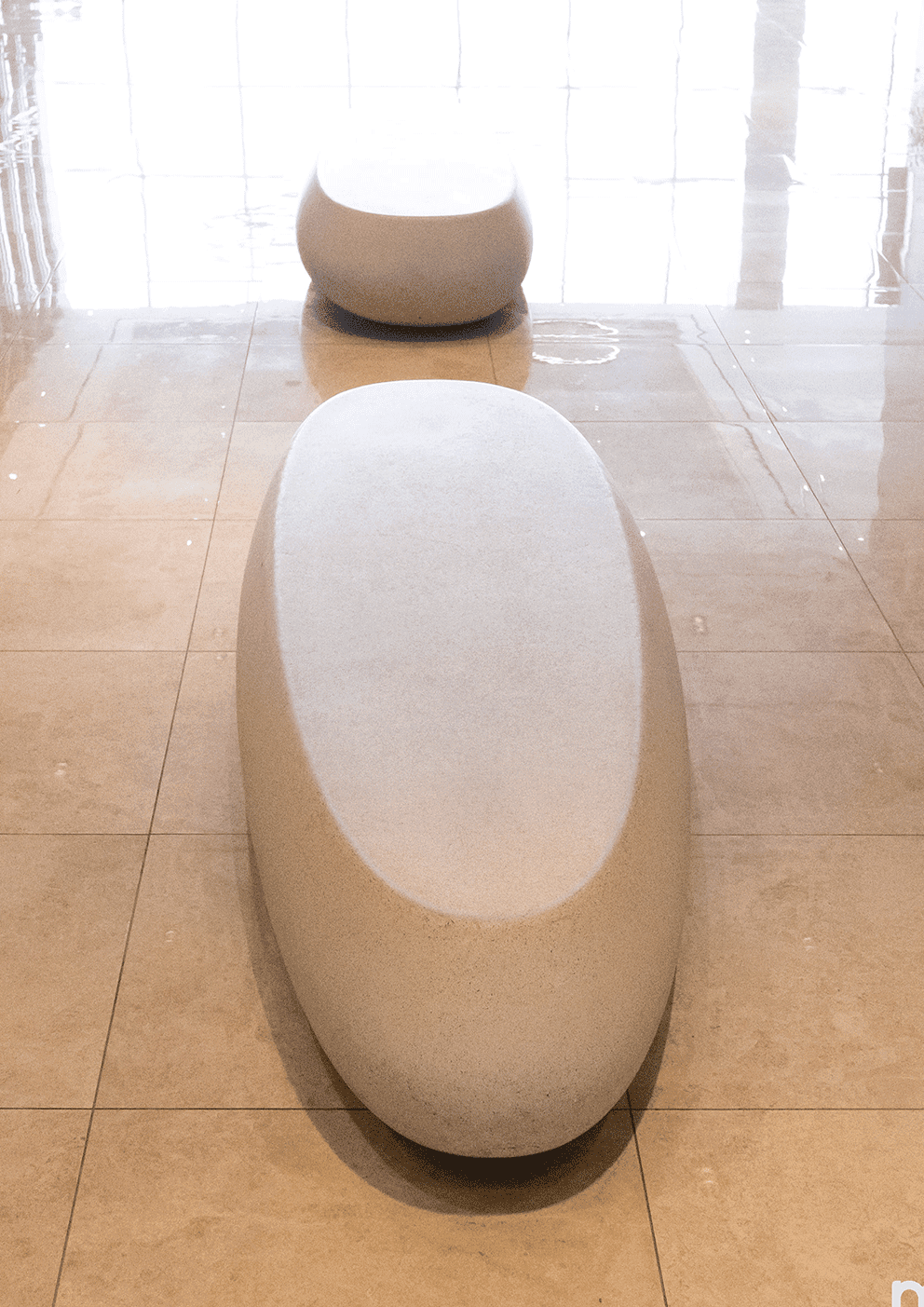 Minimalist gray-green cylindrical object with a sleek vertical base, set against a black background. Modern and clean design.
