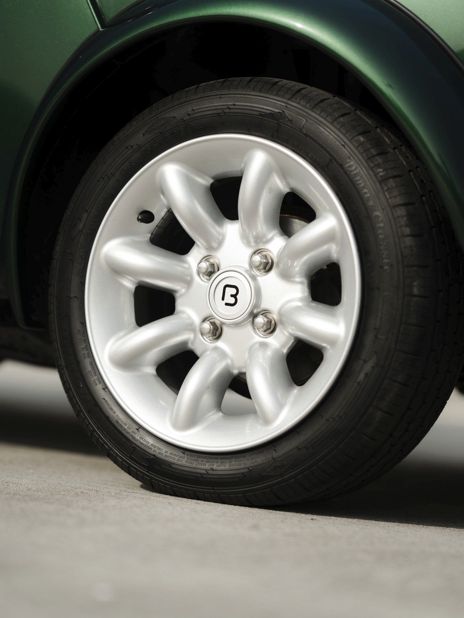 Close-up of a car wheel featuring a white alloy rim and a black tire on a smooth surface.