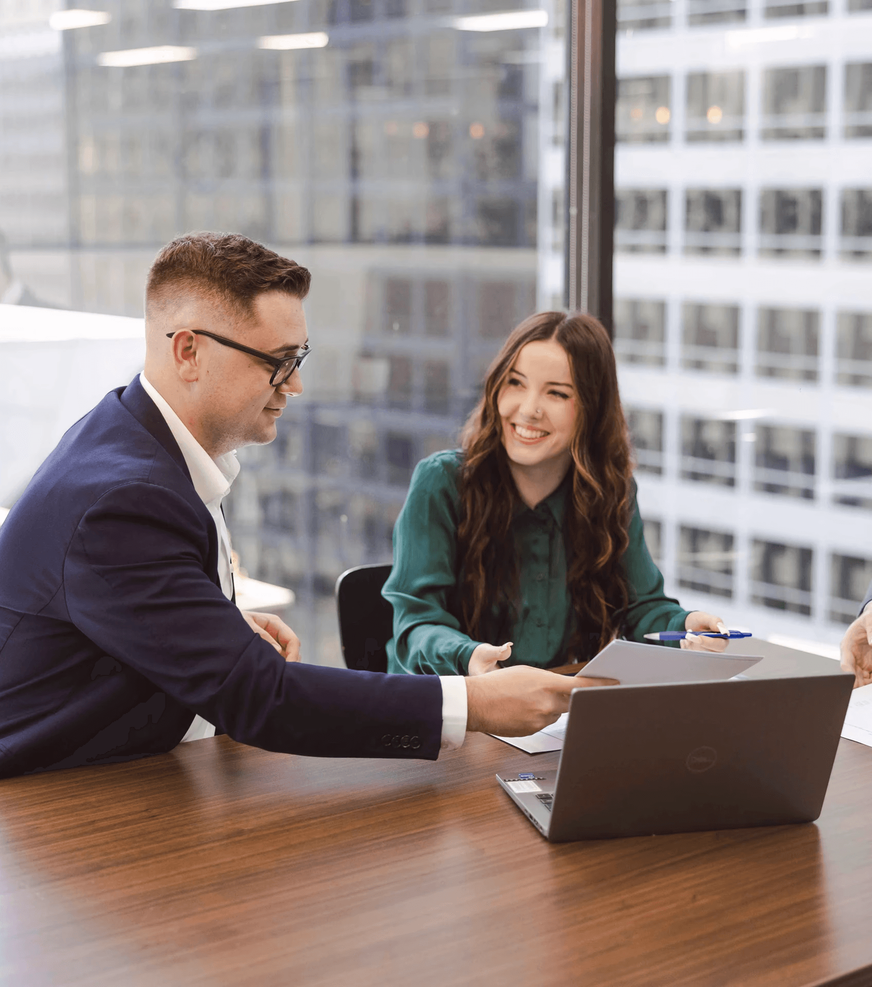 Black and white image of people working at a table with laptops, showing hands gesturing during discussion of digital content displayed on screens, with fabrica® logo in the corner.