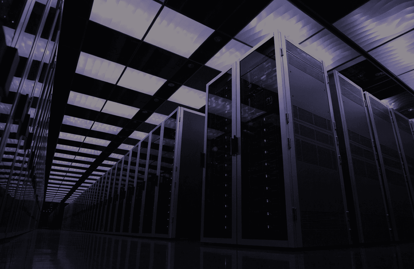 Server rows receding under a lit ceiling grid in a data hall