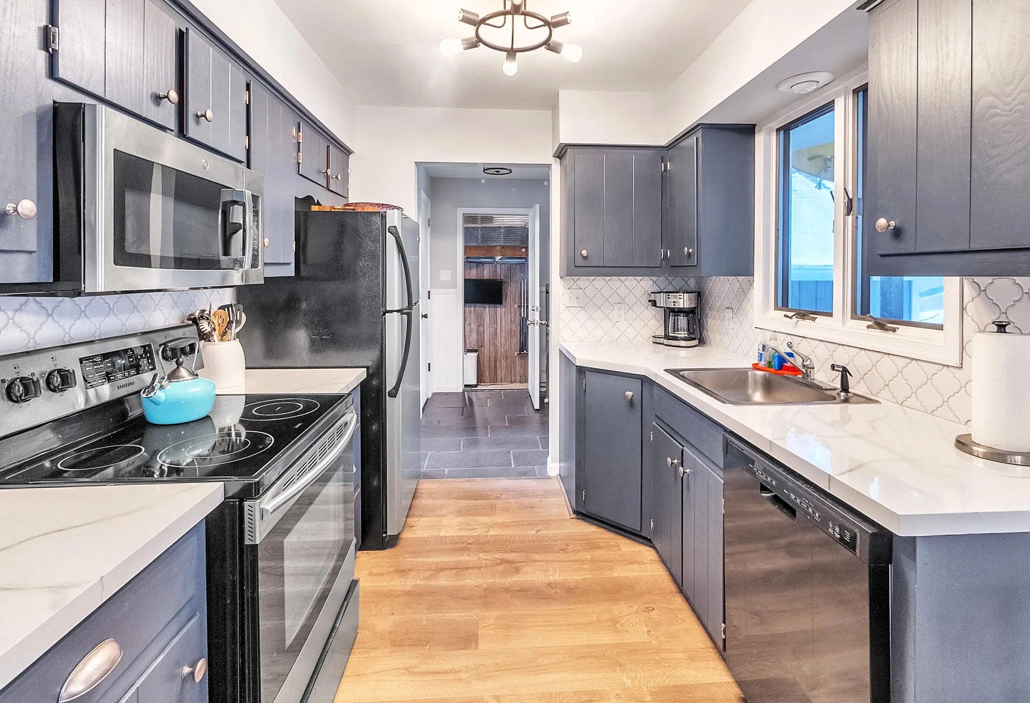 Galley kitchen with navy cabinets, white counters and stainless appliances at Beechwood Bliss