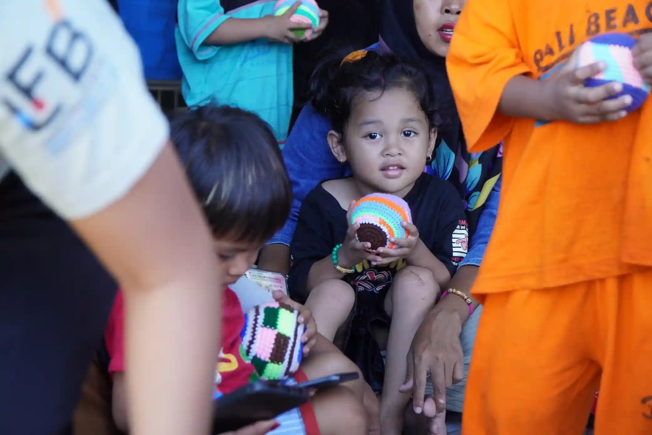 Children holding handmade crochet balls made by women in our empowerment program