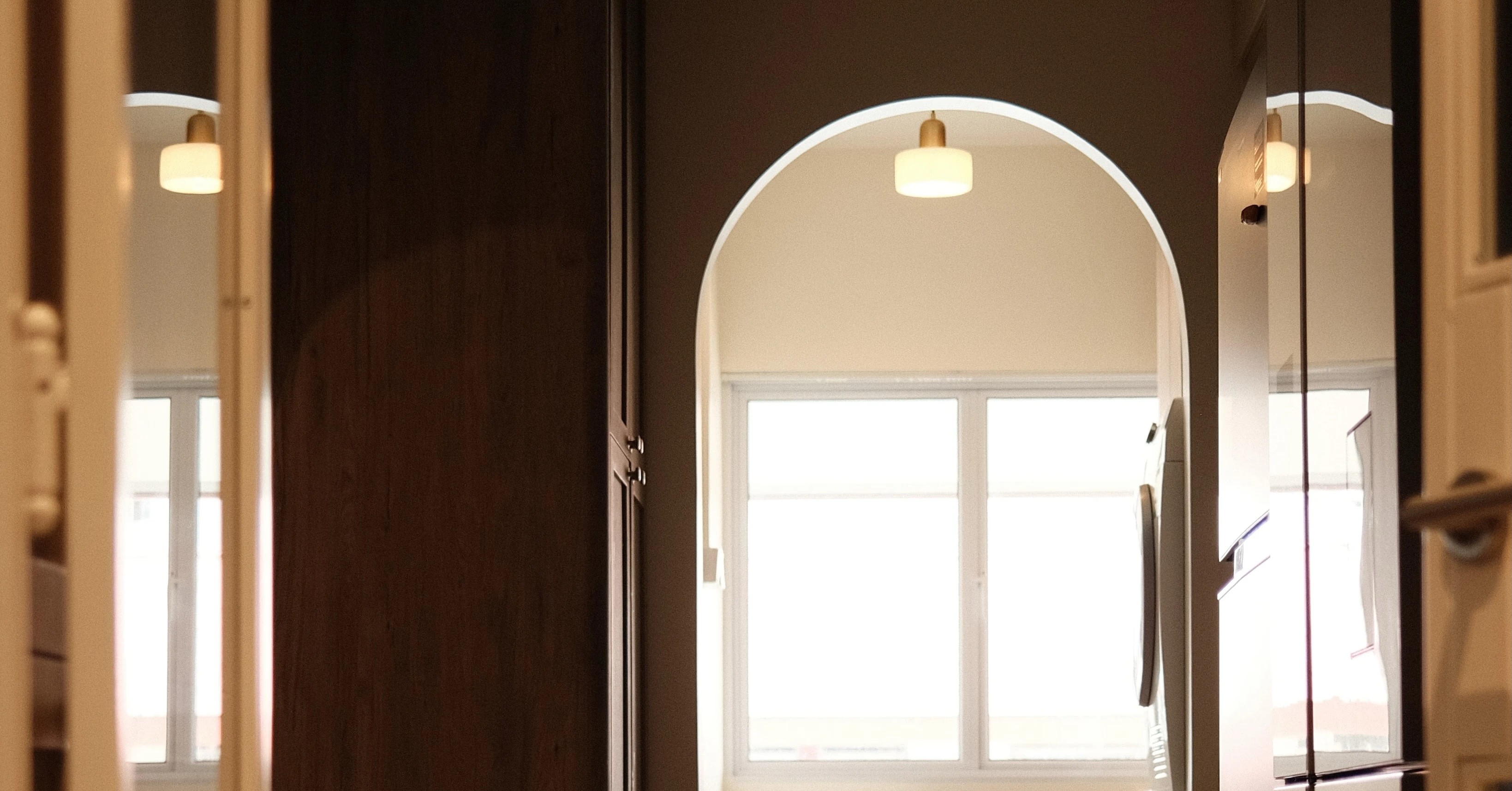 Entryway with arched doorway, natural light, and wooden details, contemporary Singapore home renovation