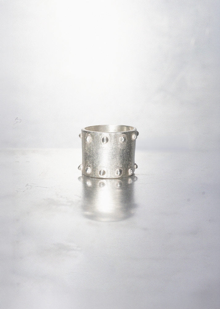 Silver ring with studs on a light gray background