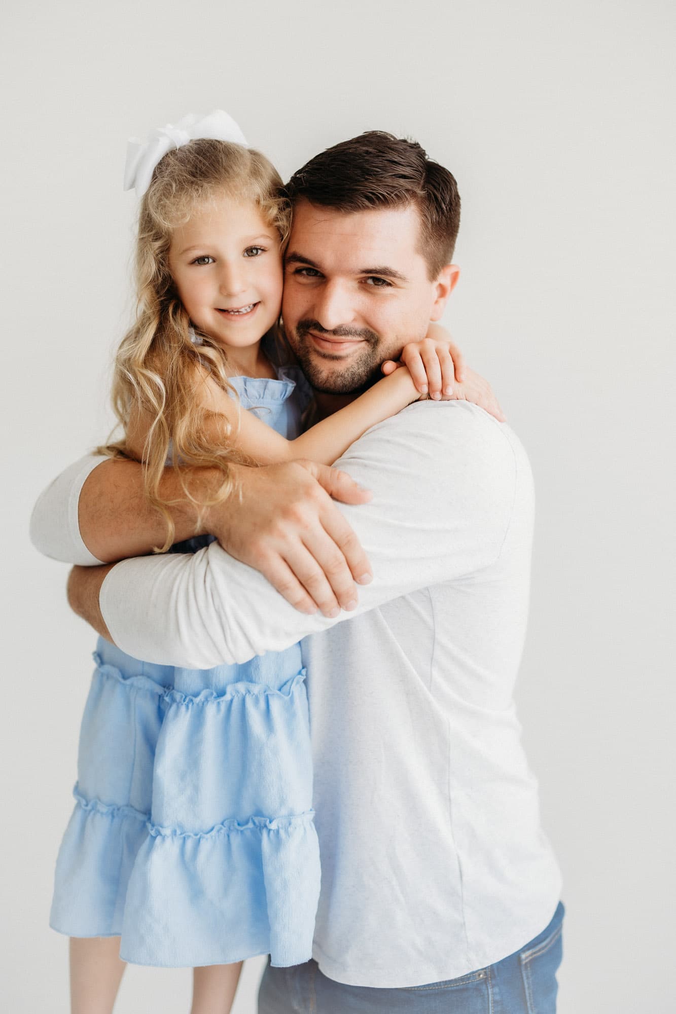 A father embraces his smiling daughter in this heartwarming moment captured at Revelator Studio, a Shreveport photography studio specializing in natural light portraits.