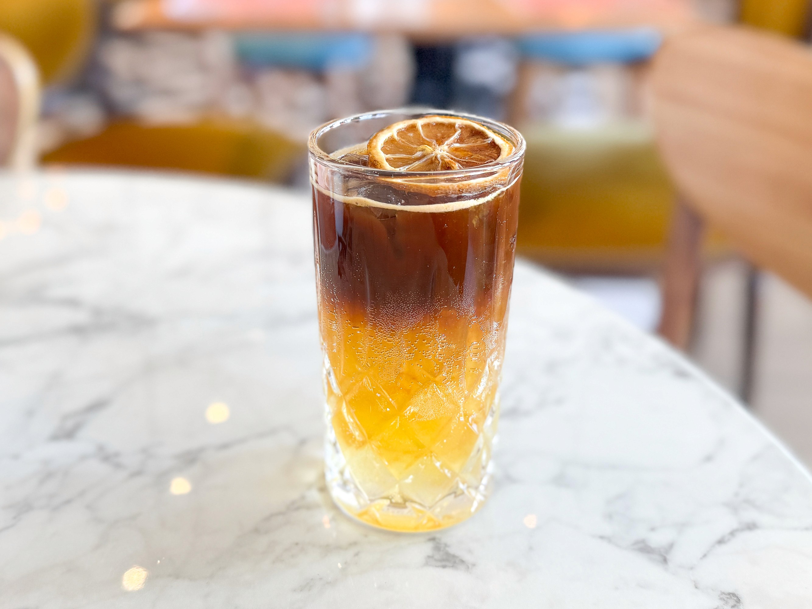 bebida fría con café en vaso de vidrio con rodaja de cítrico