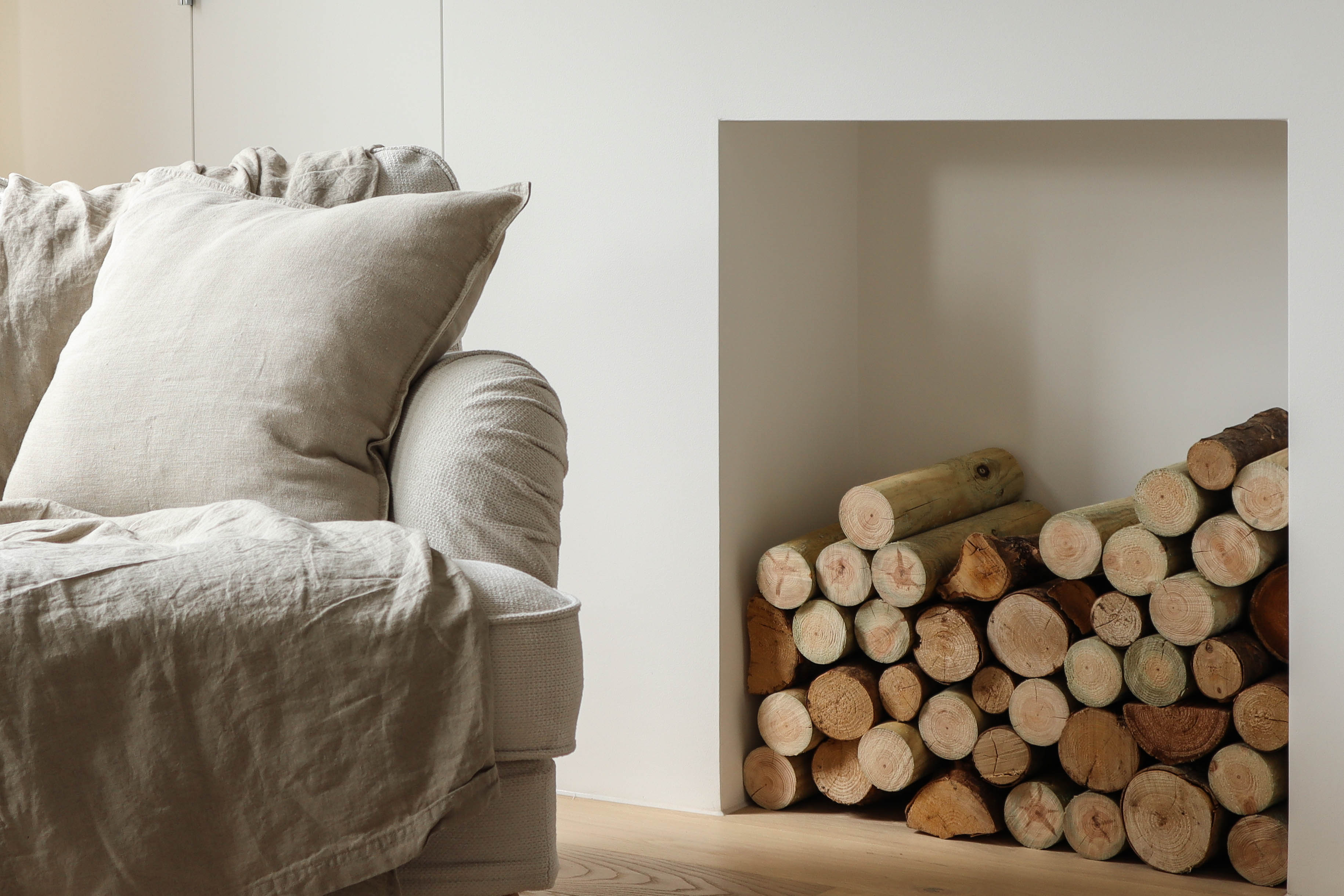 Minimalist living room with white linen couch and wood store alcove