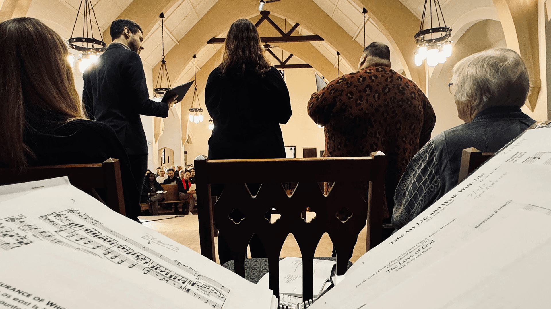 Choir singing during a service at Grace Trinity Church, with sheet music visible on the pew in the foreground.