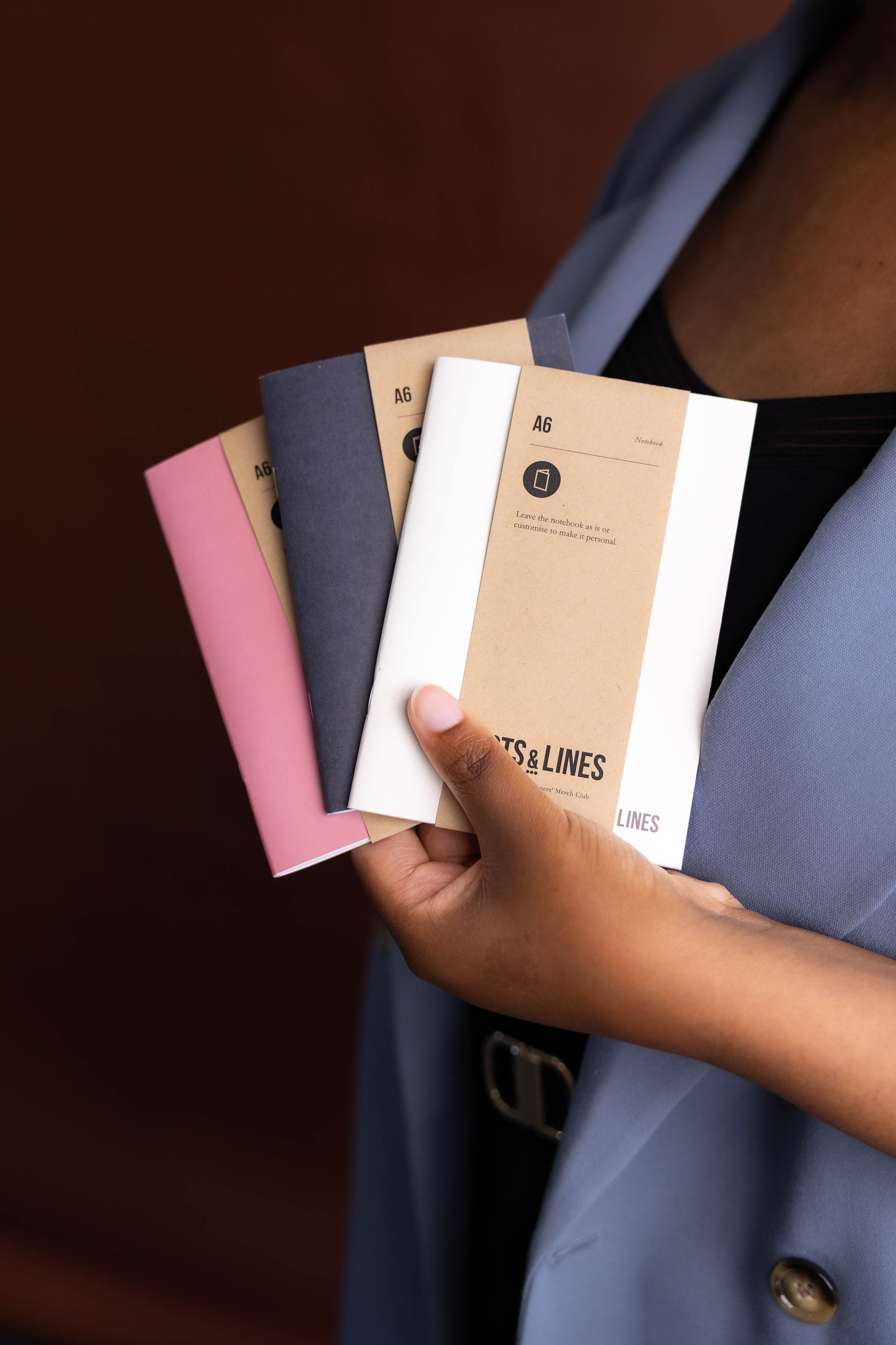 Image shows person holding 3 notebooks for a brand called Dots&Lines.