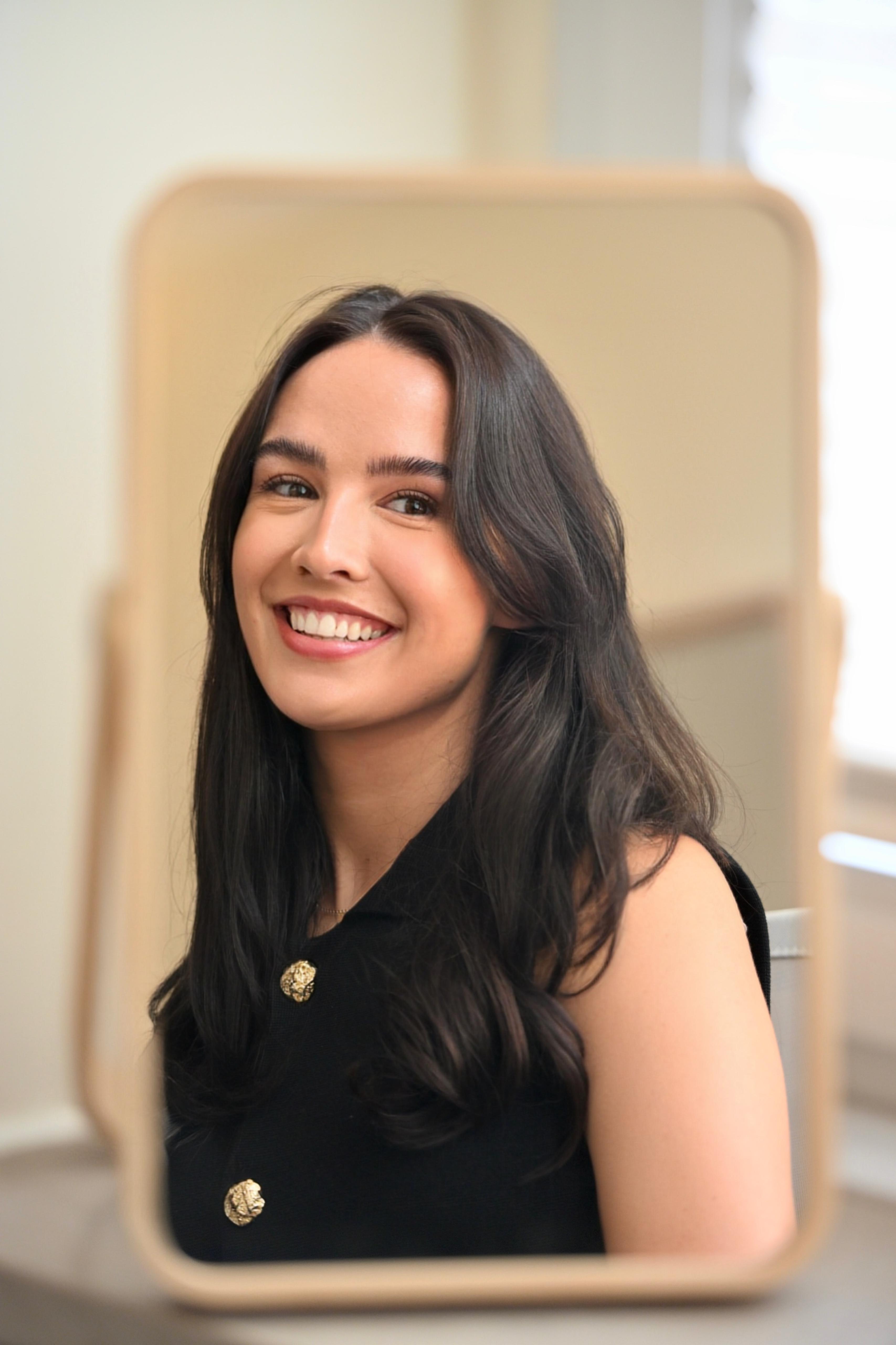 Lea Westerwalbesloh lächelt in die Kamera vor einem Spiegel – Praxis für Logopädie in Marienfeld