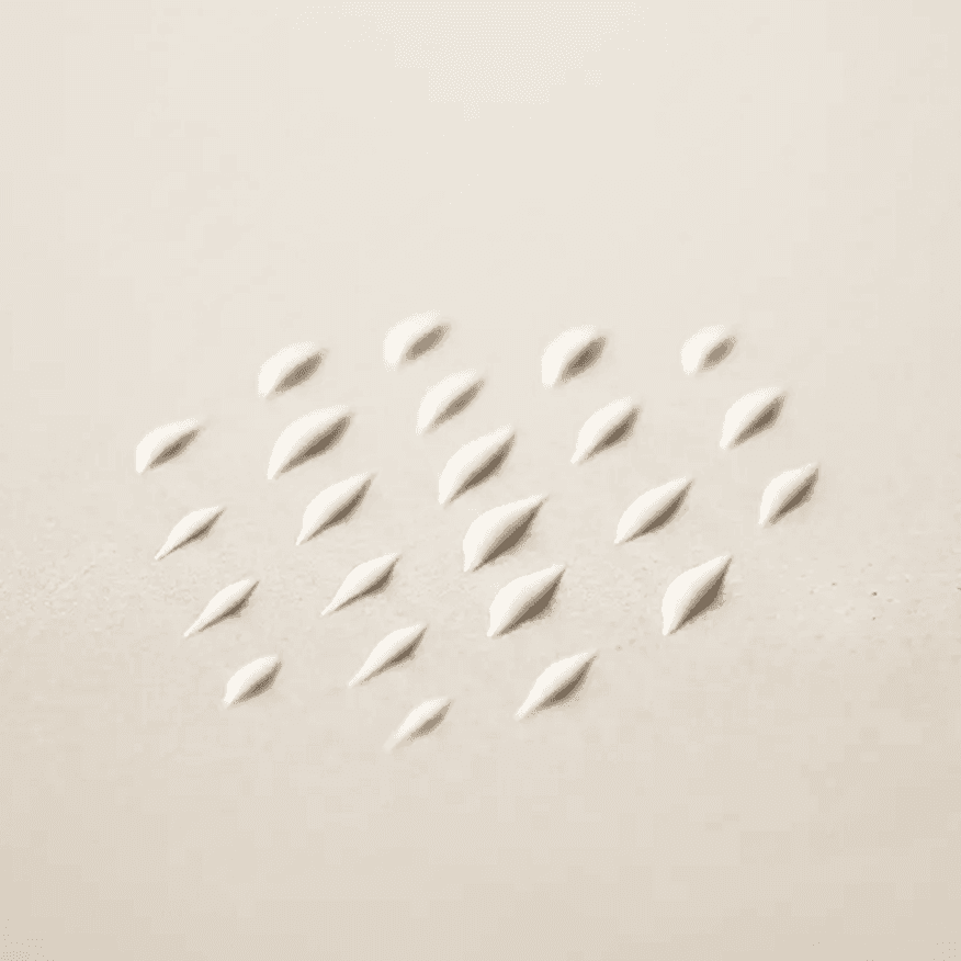 Multiple small drops of dog balm repeated across a neutral surface in a uniform arrangement