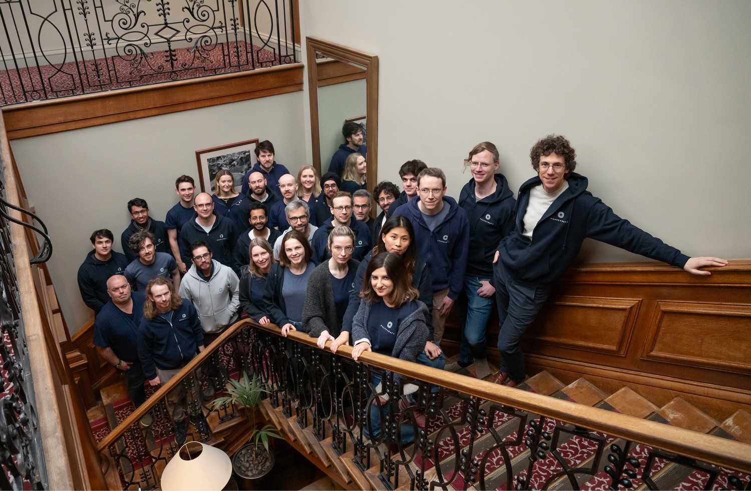 Man in a white shirt focused on a desktop computer displaying charts and data in a softly lit workspace.
