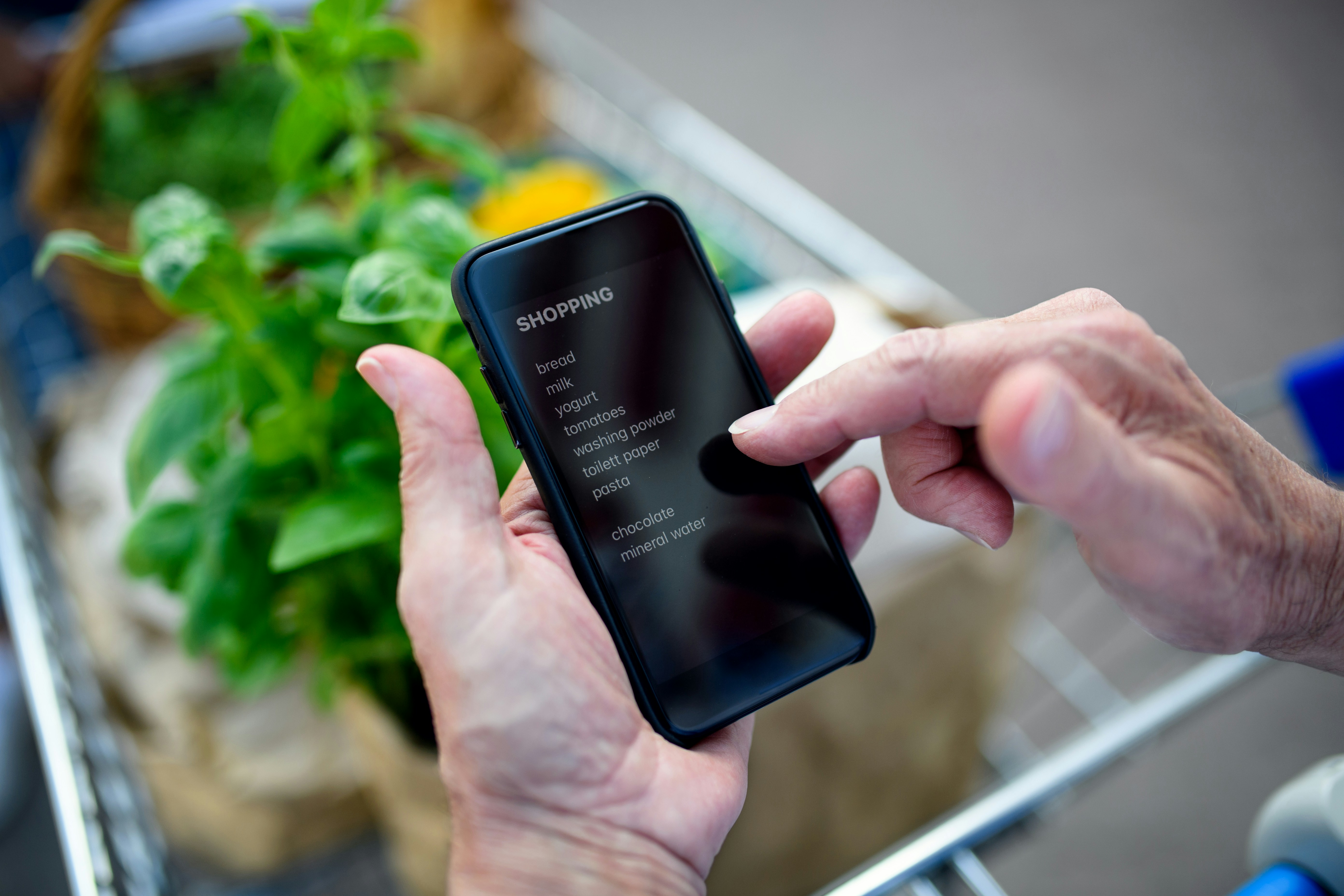 Person checking a grocery list on their phone while shopping.
