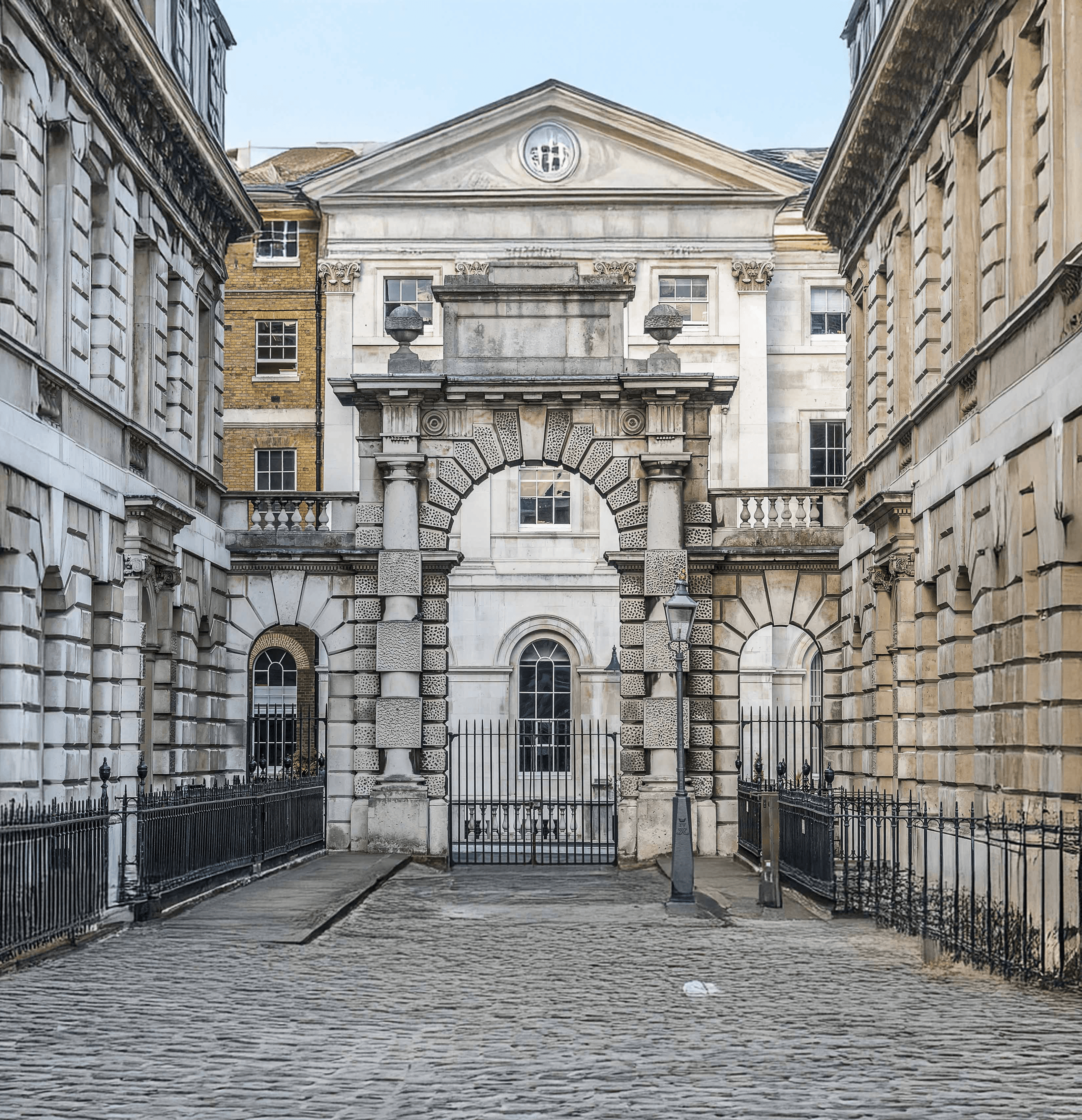Historic stone archway between classical London buildings, symbolising controlled access, permanence, and long-term wealth structuring.