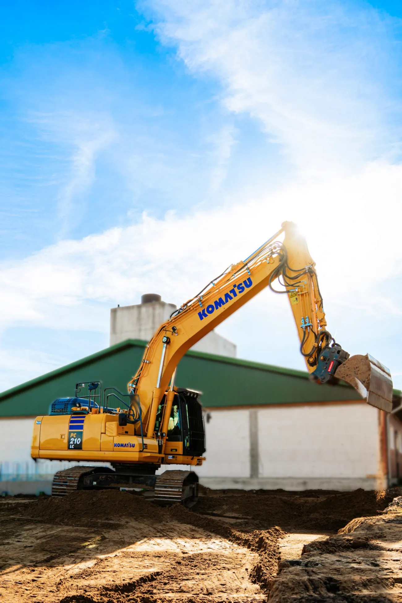 Gelber Komatsu-Kettenbagger PC210 hebt bei Erdarbeiten die Schaufel