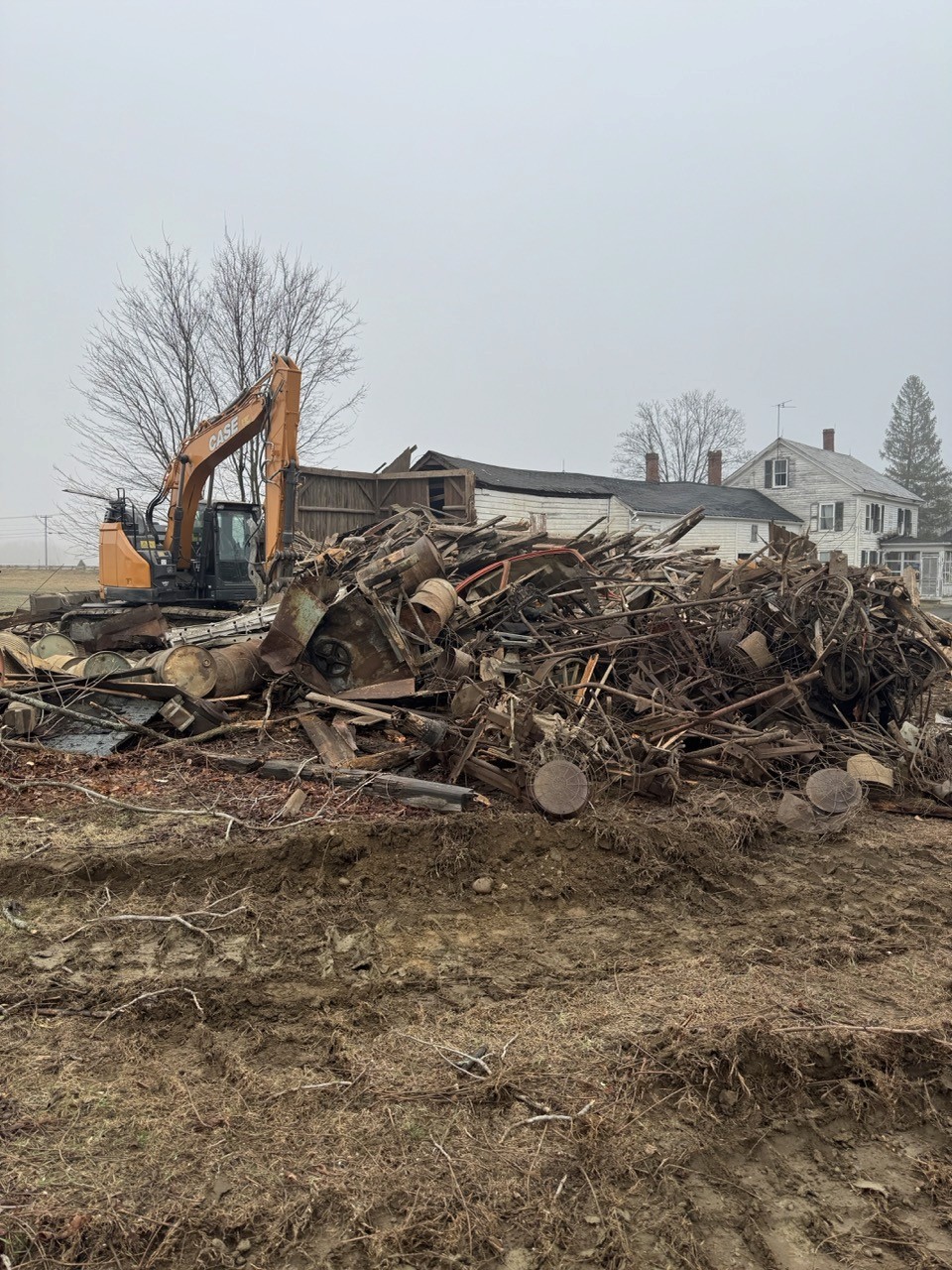 Excavator sorting timbers during barn demolition, by A&M Construction Enterprises