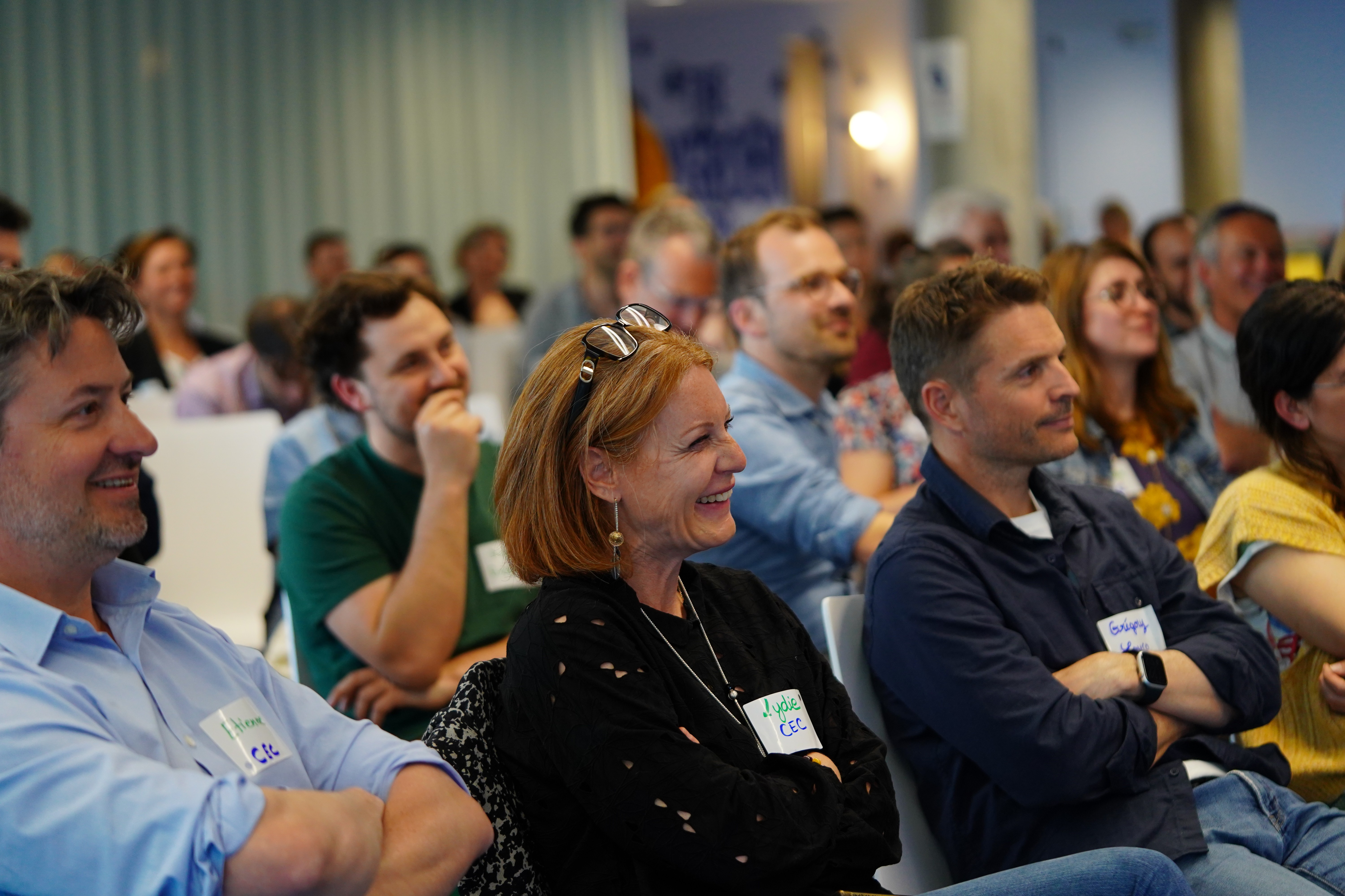 Smiling young man with short hair poses against a dark background, wearing a green button-up shirt.