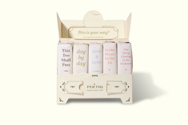 A white box containing four books titled “This Too Shall Pass,” “day by day,” “again & again,” and “In the Ocean In the Air” is shown against a white background. The box has a lid with the phrase “This is your song!” printed on it. The word “POETIQ” is visible on the front of the box.