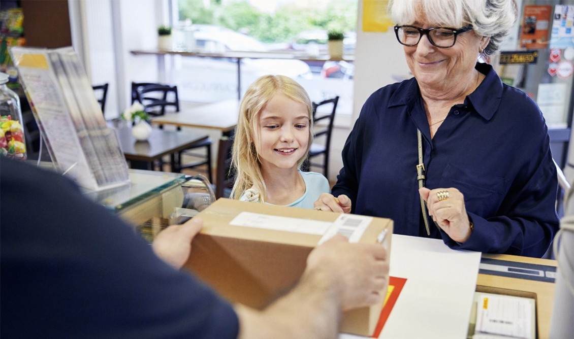 Customers happily receiving a parcel at a shop counter
