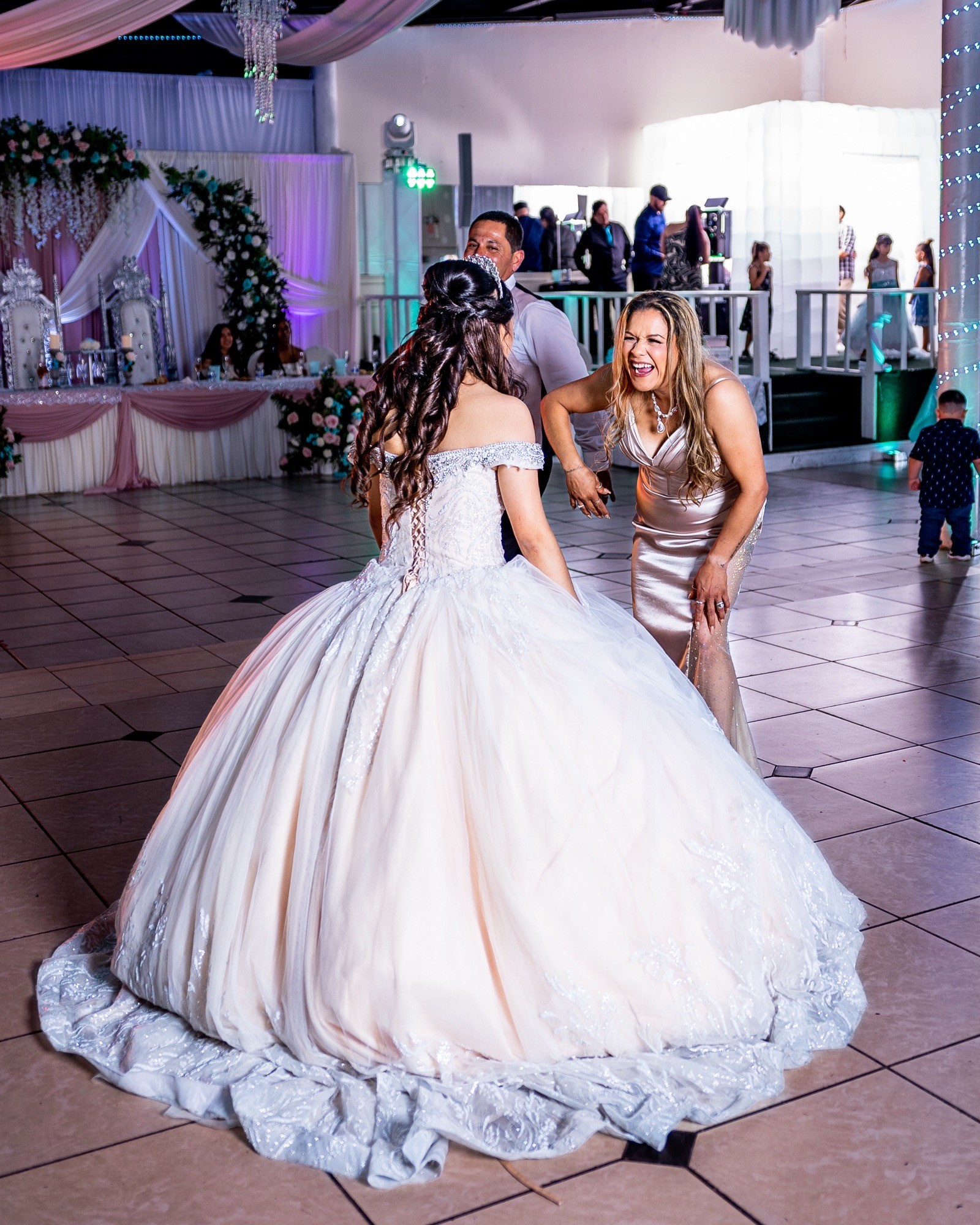 Quinceañera con vestido blanco bailando con una invitada en su fiesta