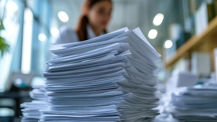 A stack of papers with a woman in the background
