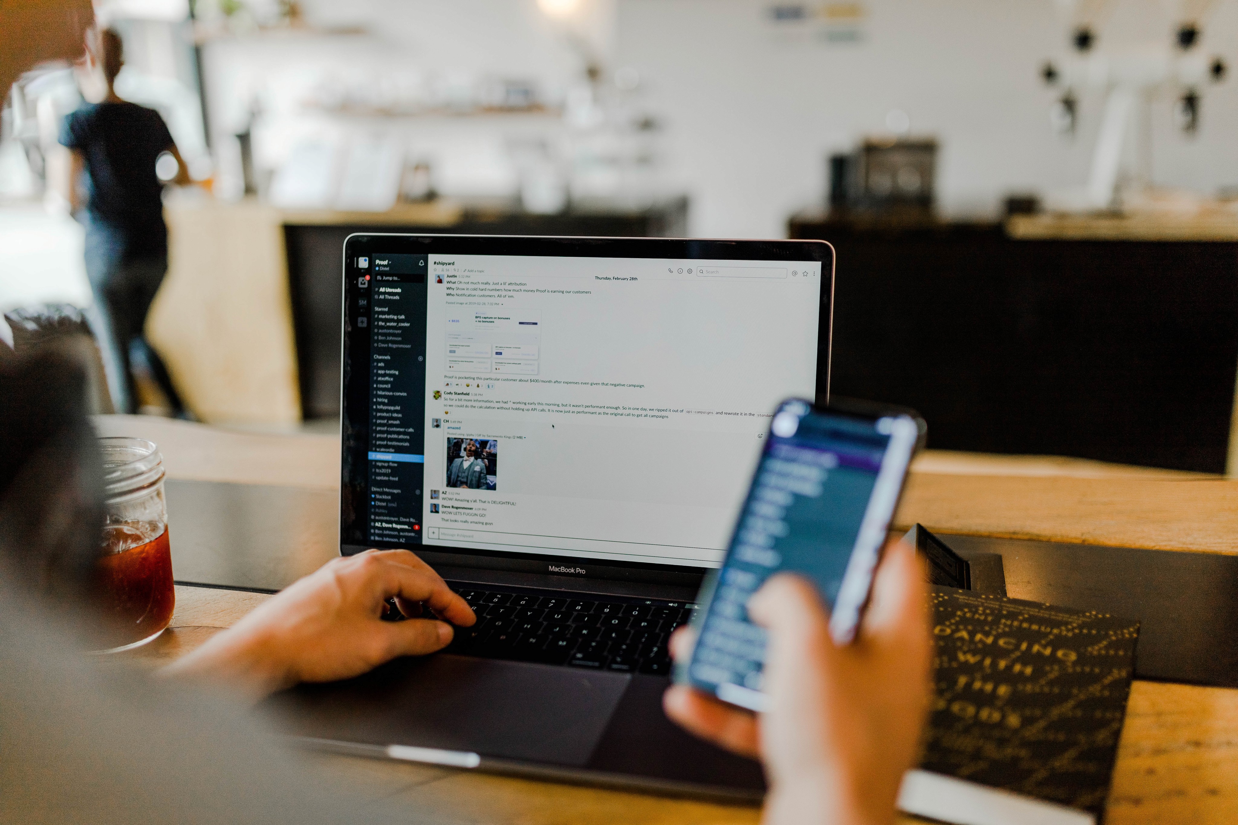 Person holding phone and using laptop at the same time to show the challenge of online community engagement