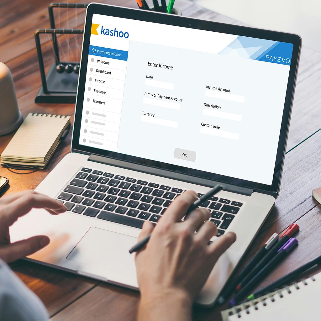 Person typing on laptop showing Kashoo income entry form with PaymentEvolution integration interface