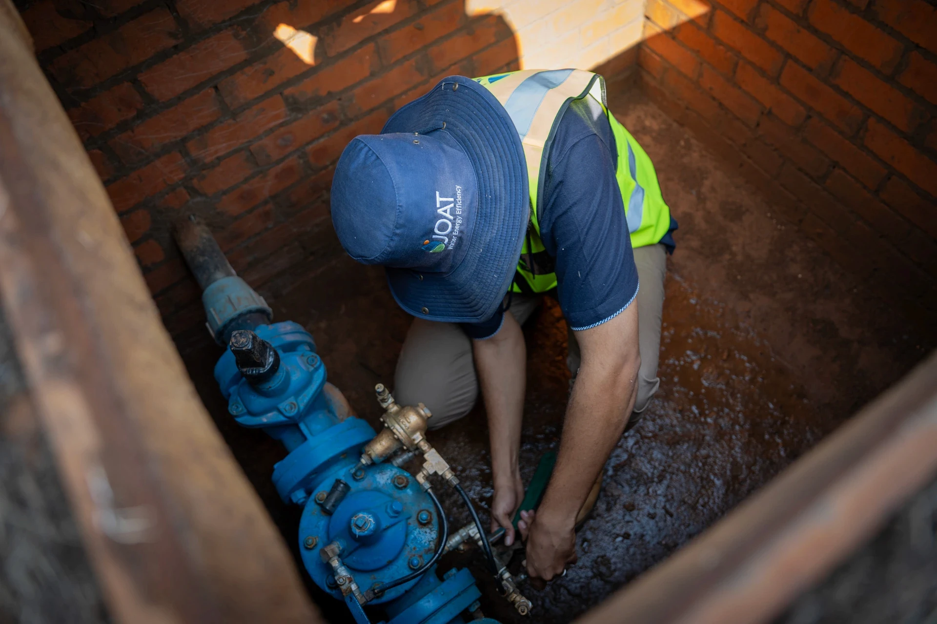 JOAT technician servicing a pressure reducing valve inside an underground chamber