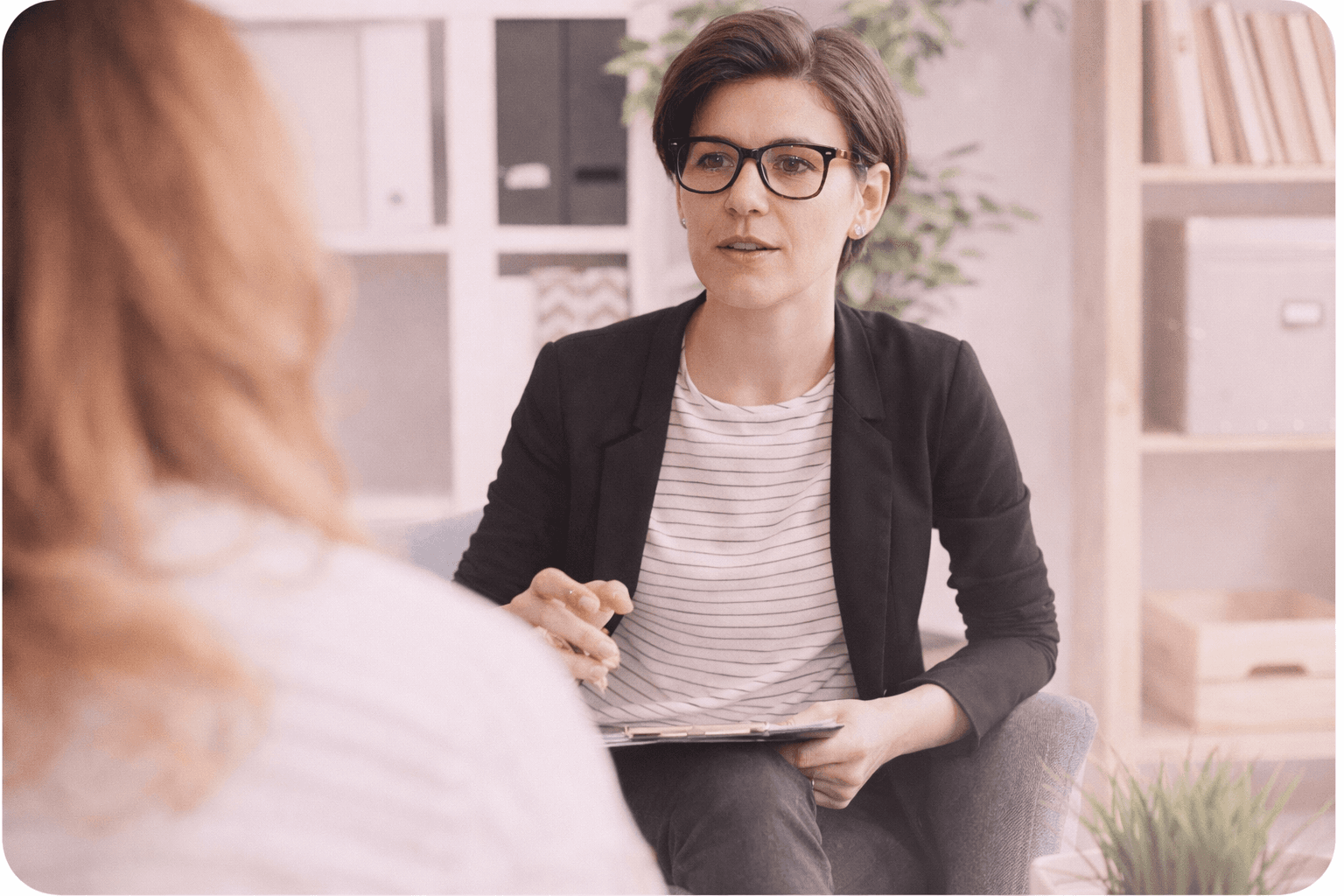 a woman sitting on a couch talking to another woman