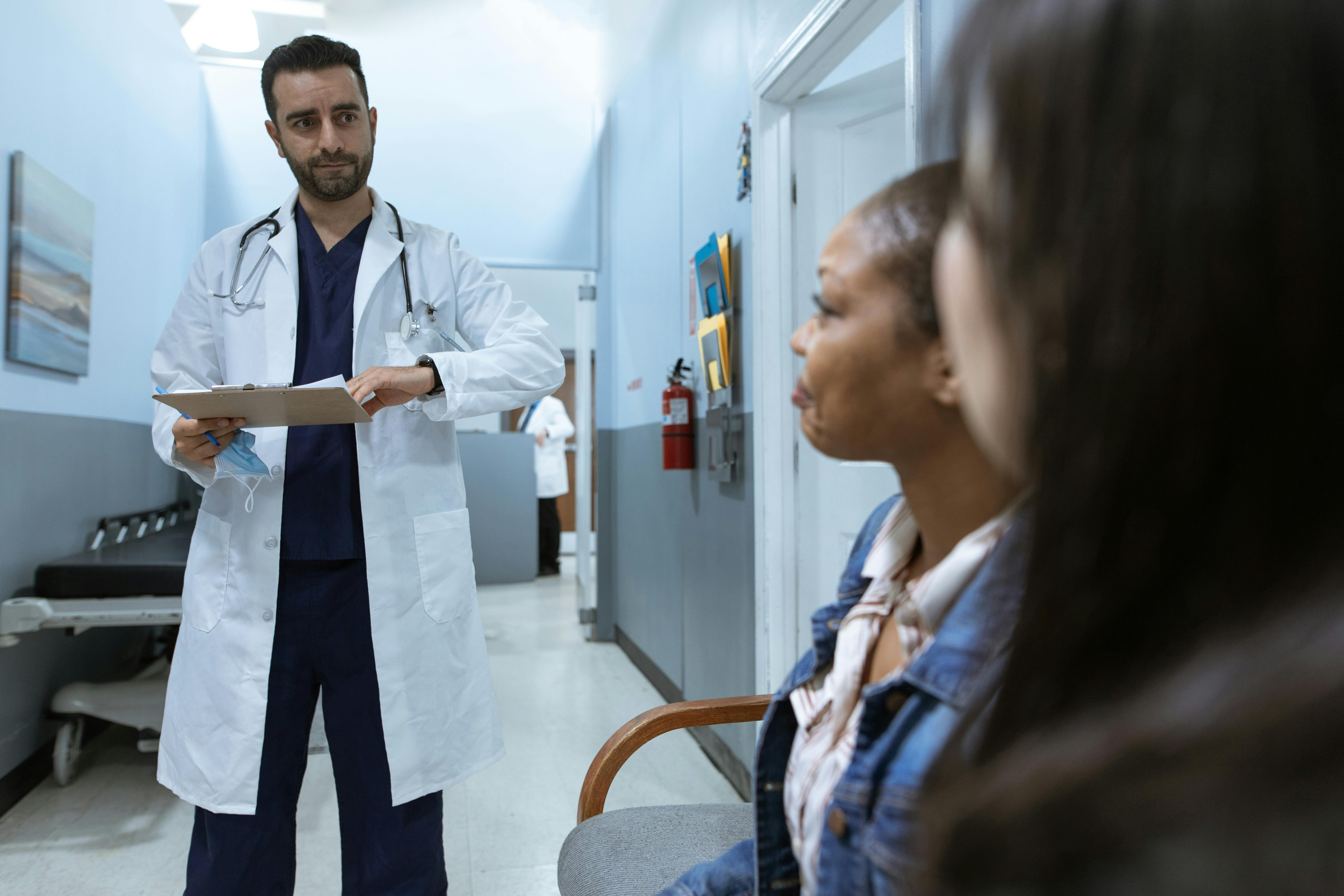 A picture of doctor with clipboard calling patients from clinic waiting area