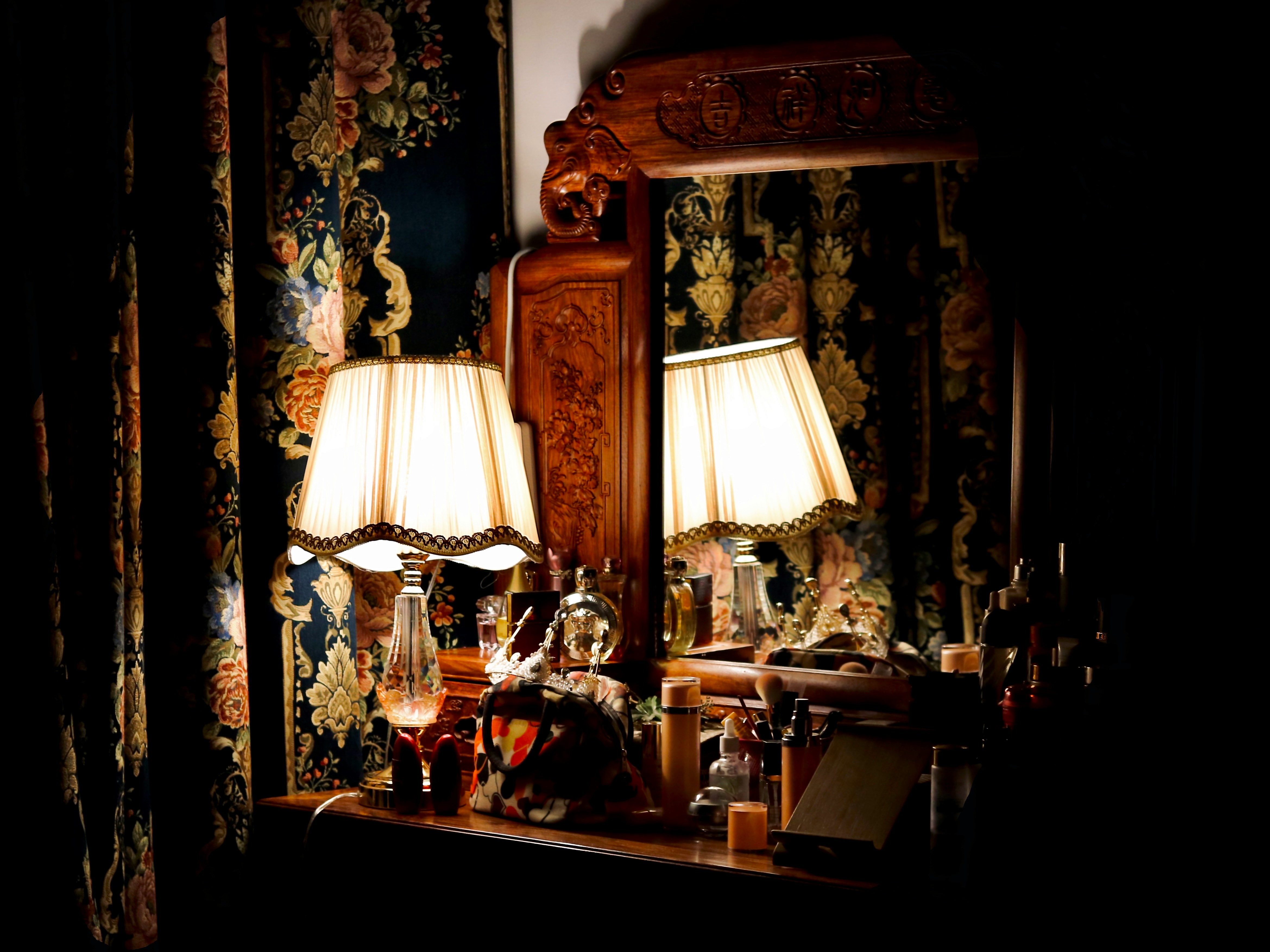 A traditional dressing table illuminated by a softly lit lamp.