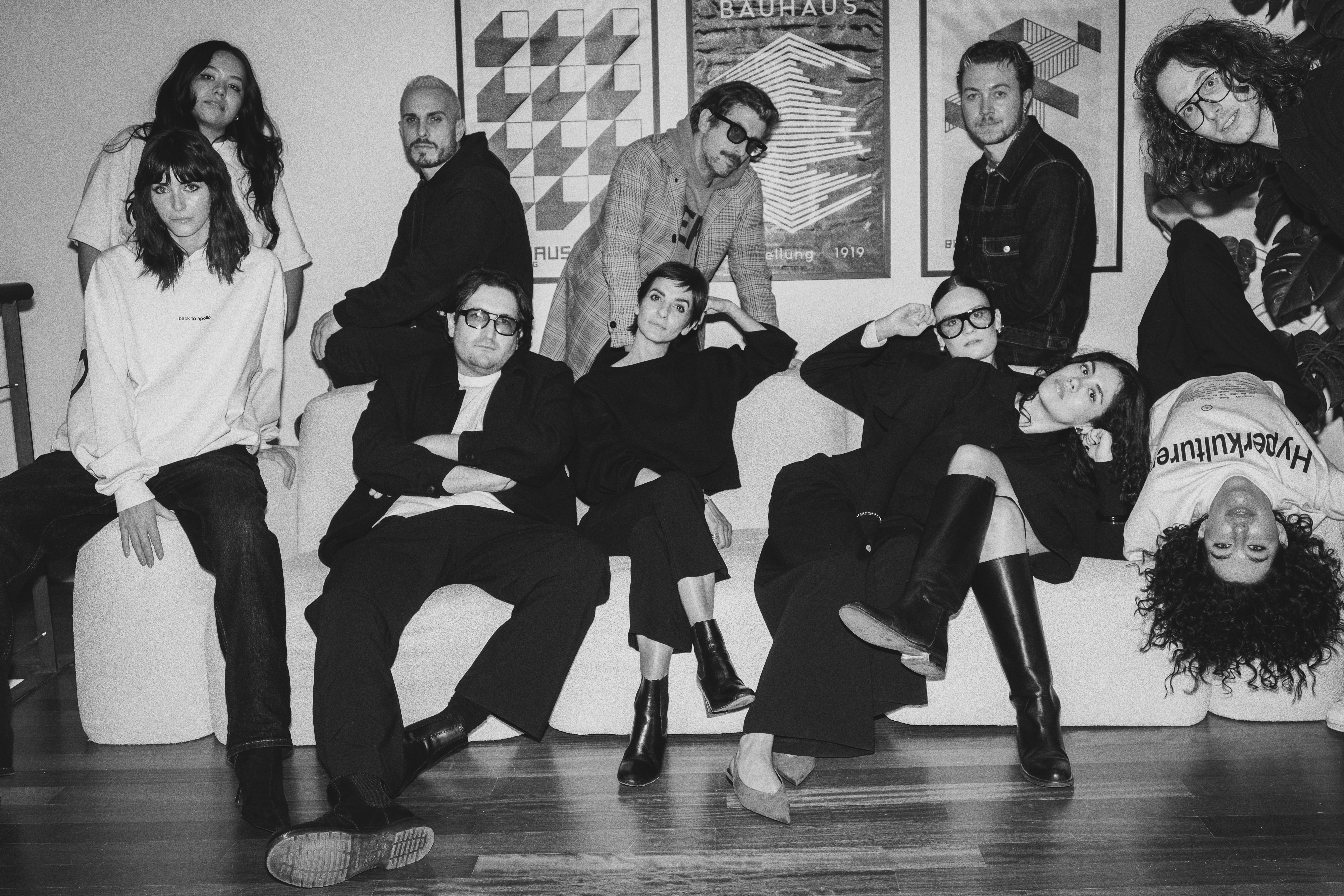 A large group photo of diverse team members gathered in an industrial-style space with arched ceiling.