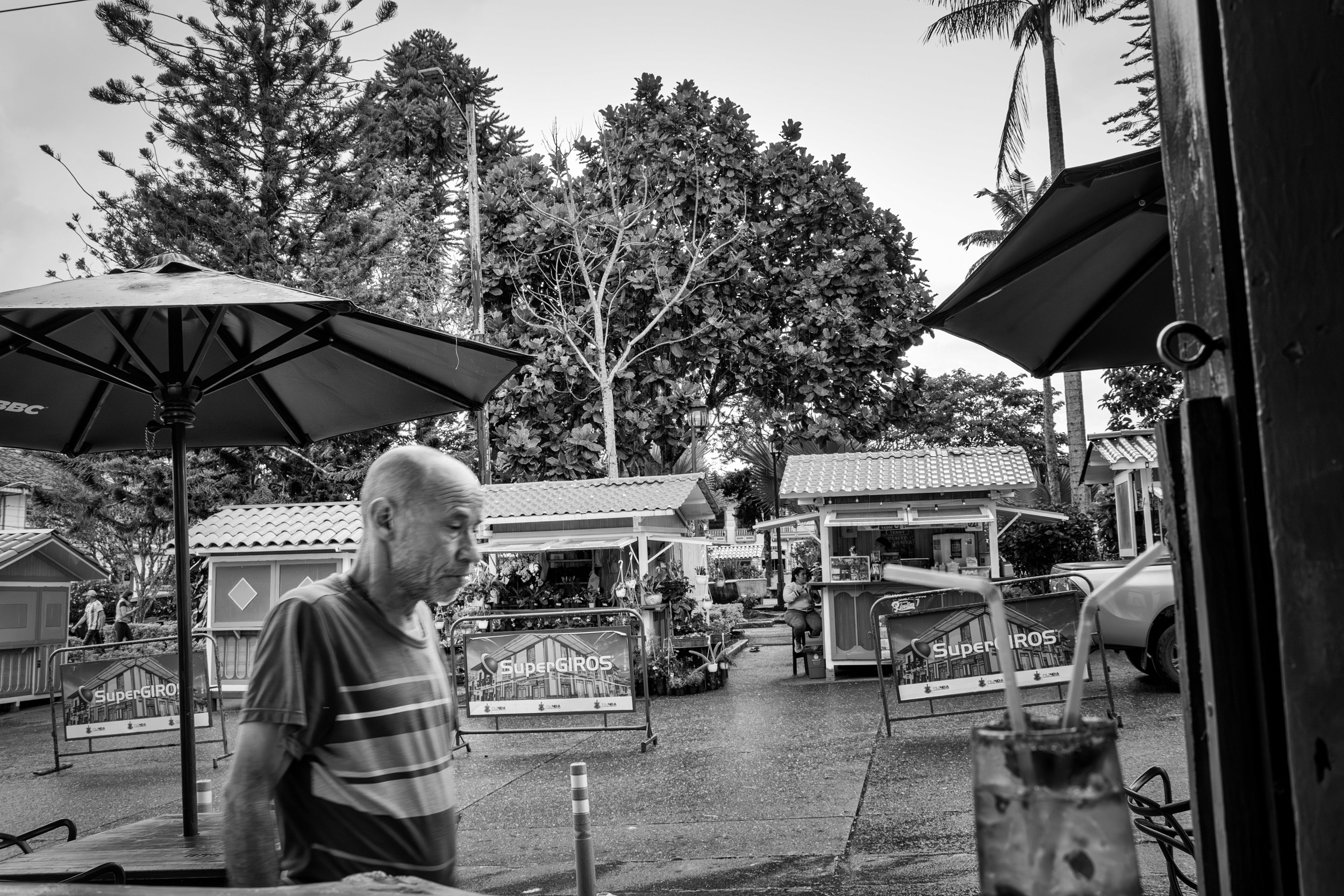 Rainy street scene with people passing by a bar window.