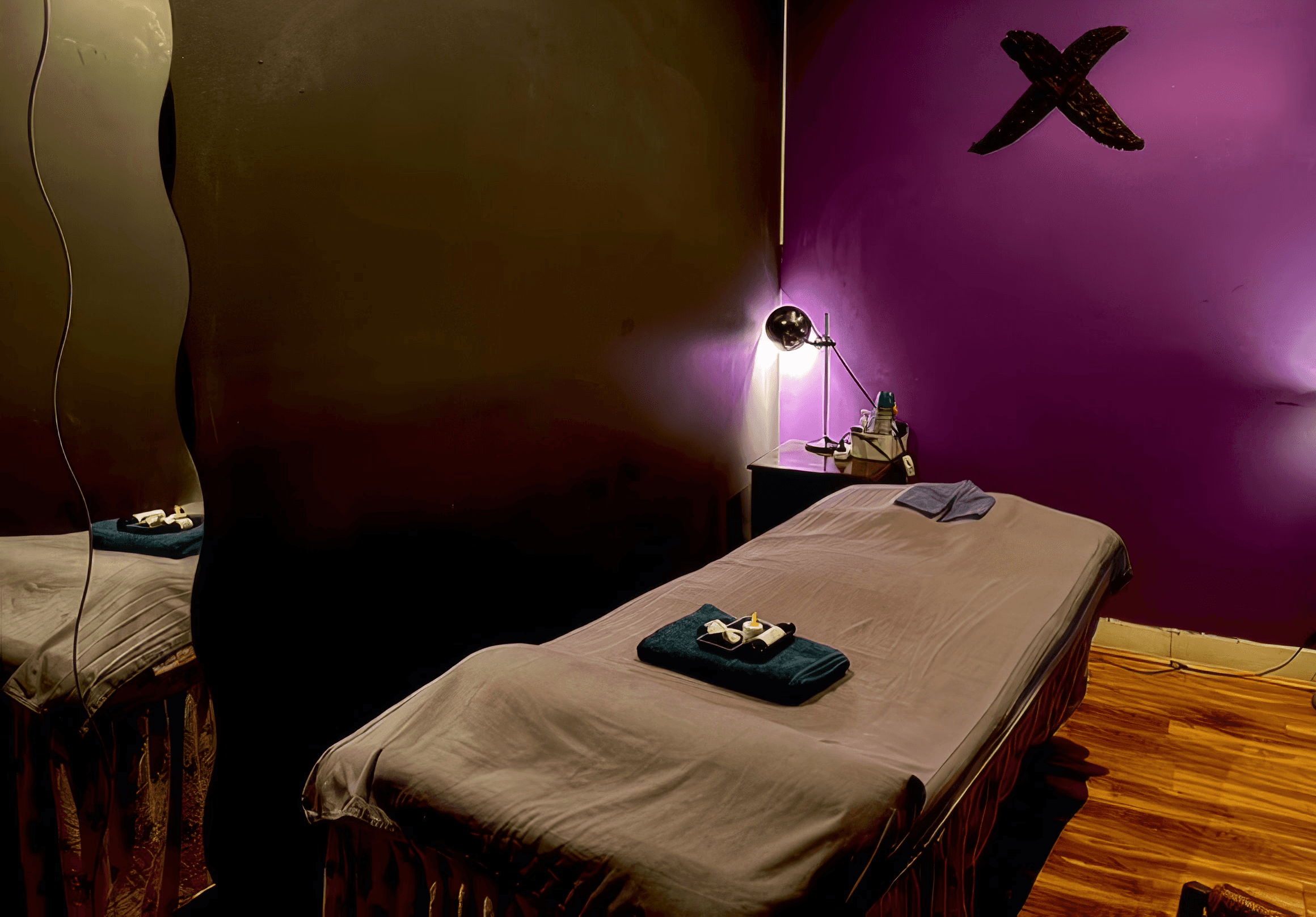 A serene and elegant spa space with wooden reclining chairs and white cushions. Golden sunlight filters through a cascading water feature, creating a peaceful atmosphere. Tropical plants and candles add to the relaxing ambiance.